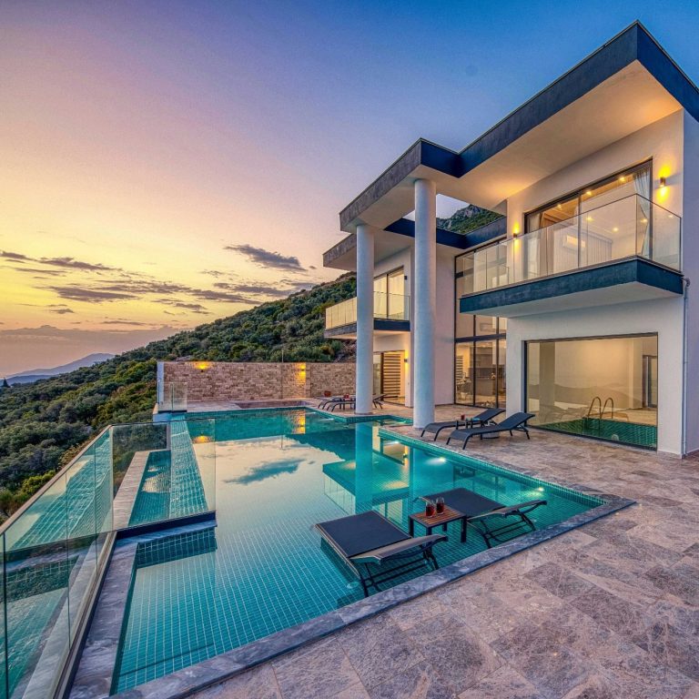 Travelowpay.com Modern villa with a pool and sunset views over a hillside.